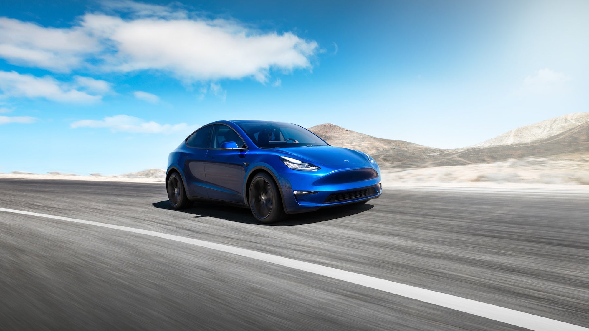 A blue Tesla driving on an open road.