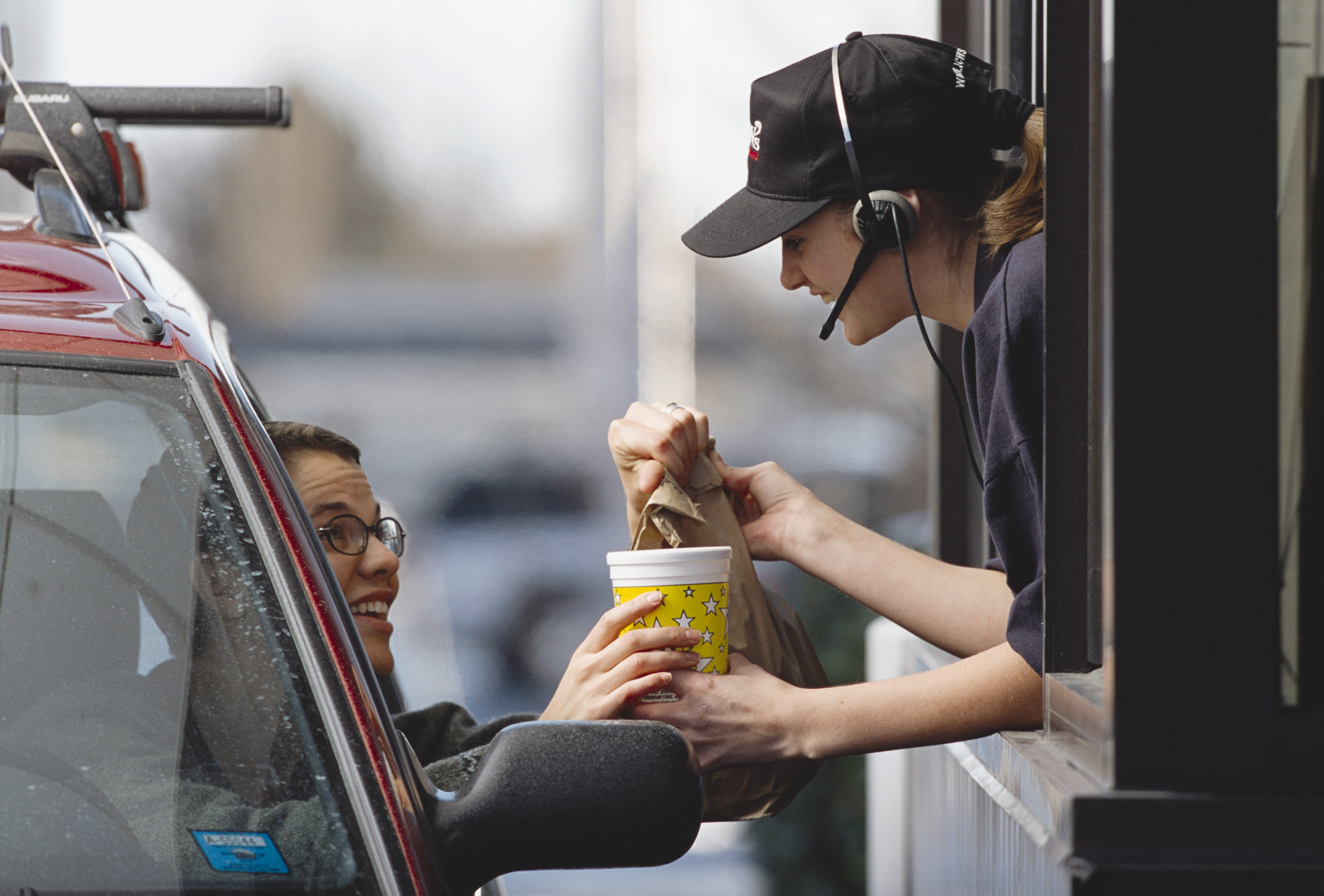 A person collecting their food at the drive-thru window of a restaurant.