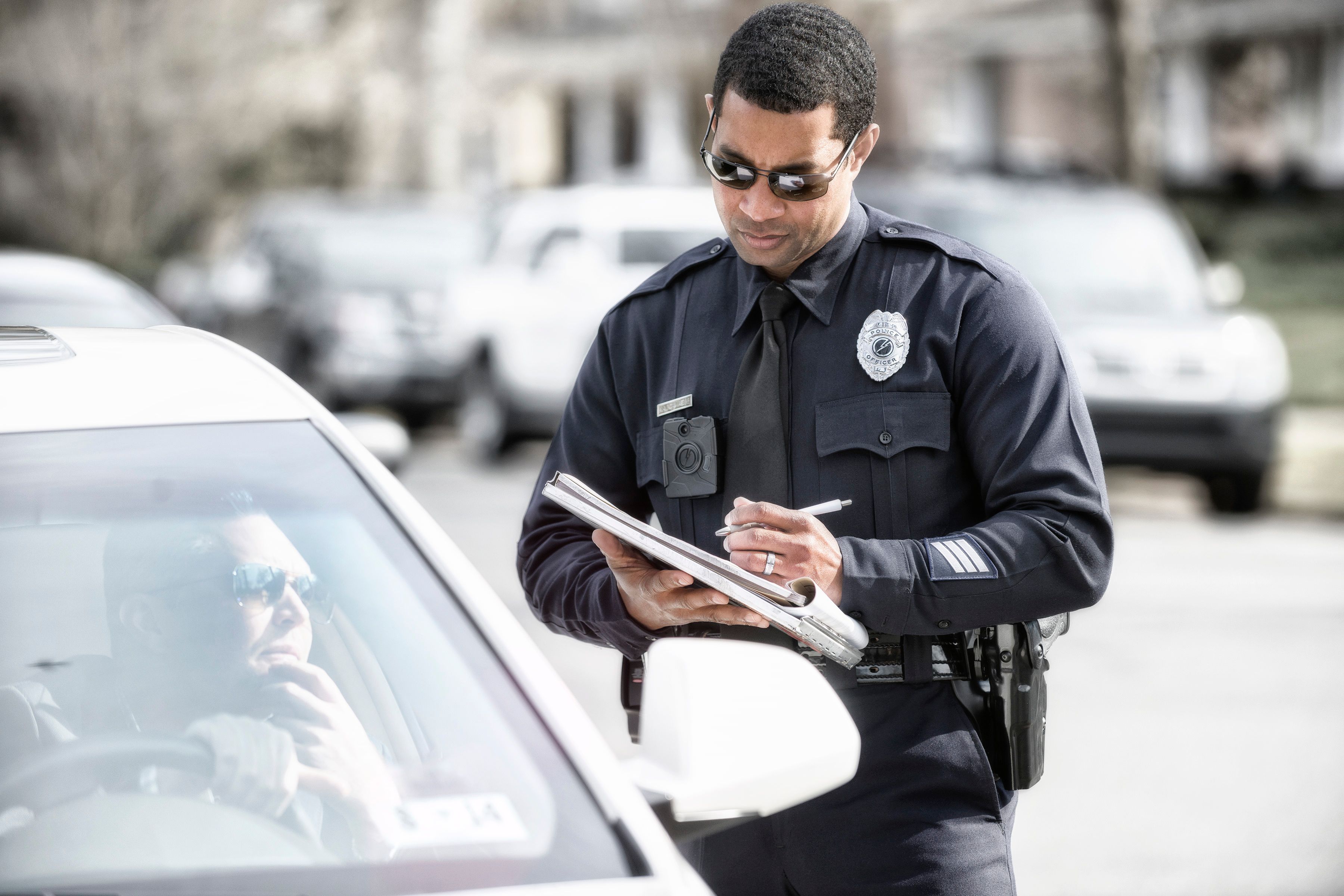 An officer writing a ticket while wearing an Axon body camera.