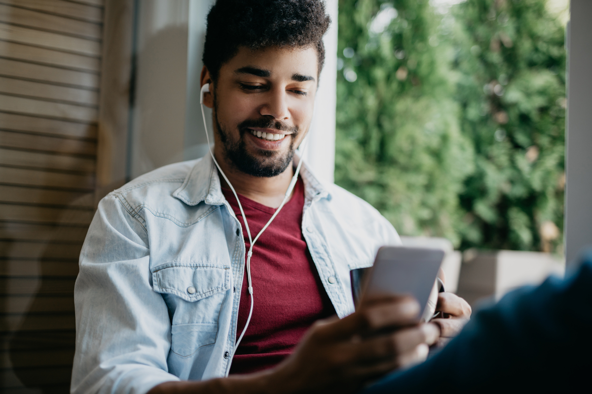 A person looking at their smartphone and listening through headphones.