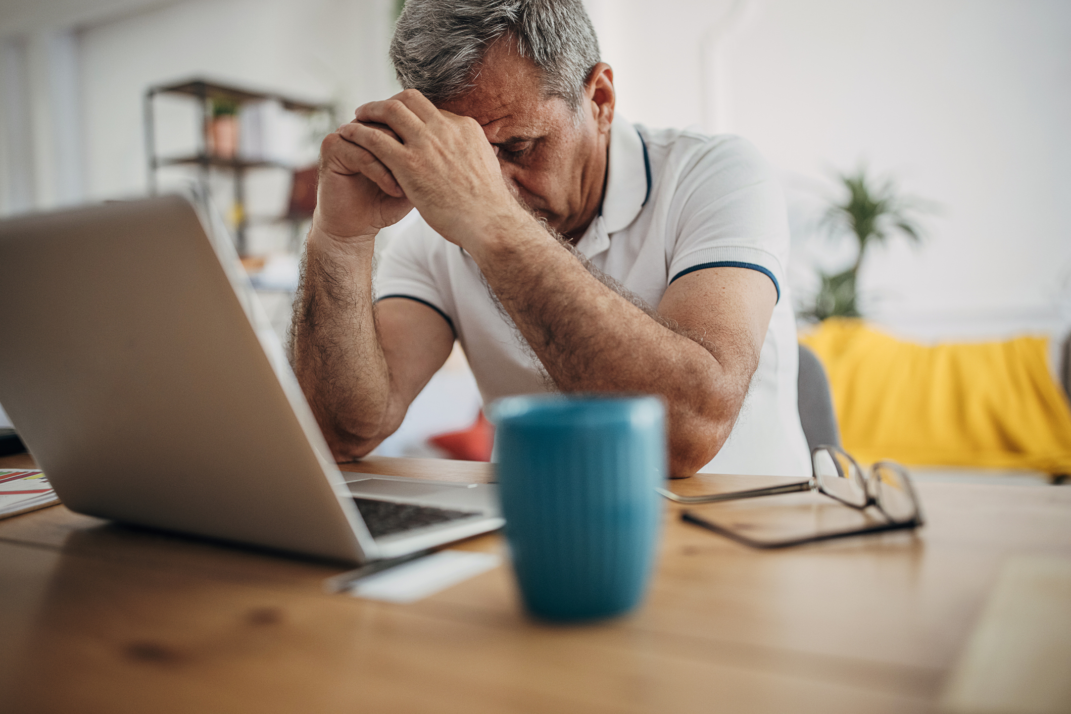 Stressed person with head in hands sitting in front of laptop.