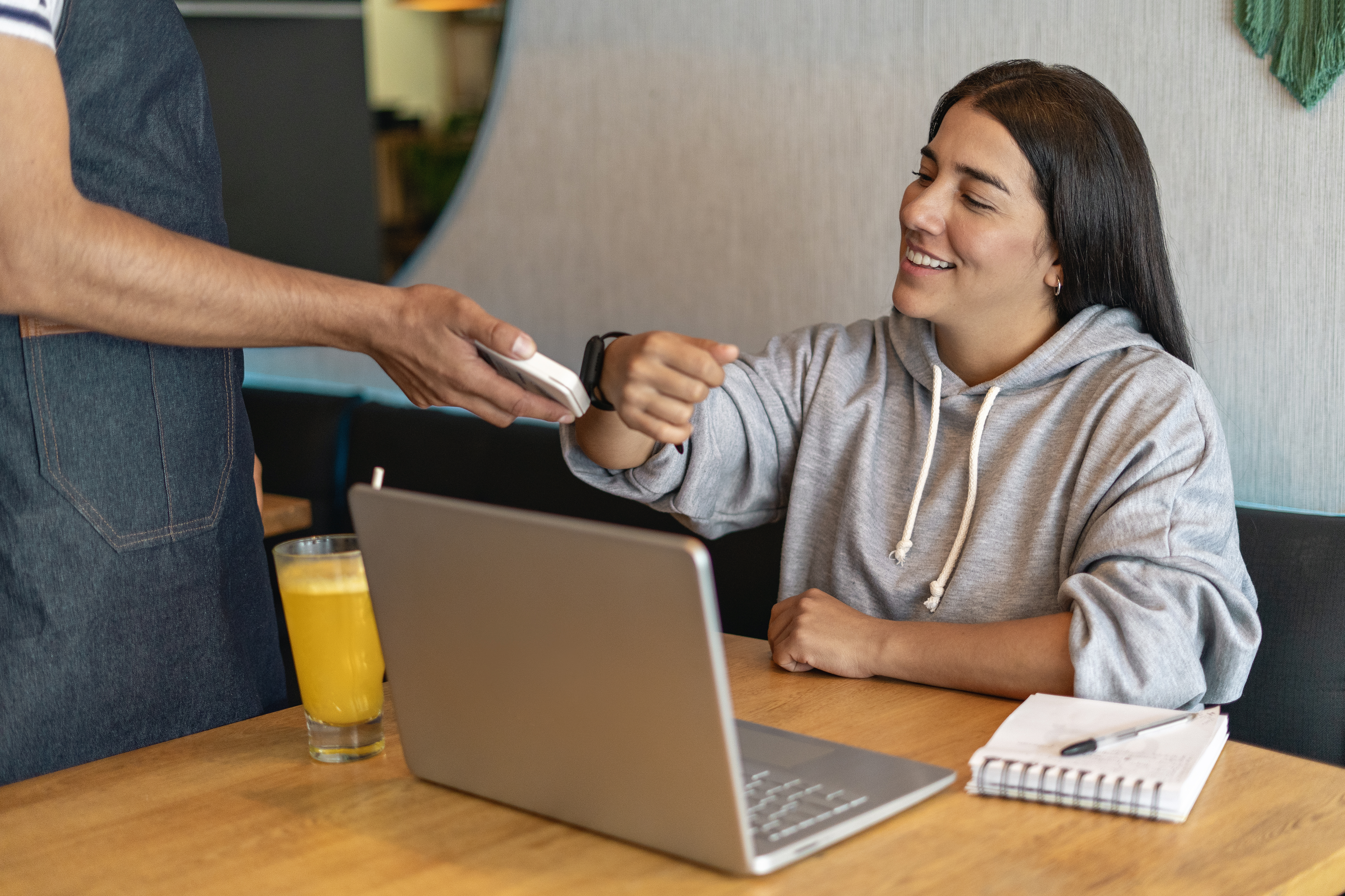 Person making a payment in a coffee shop using a smartwatch.