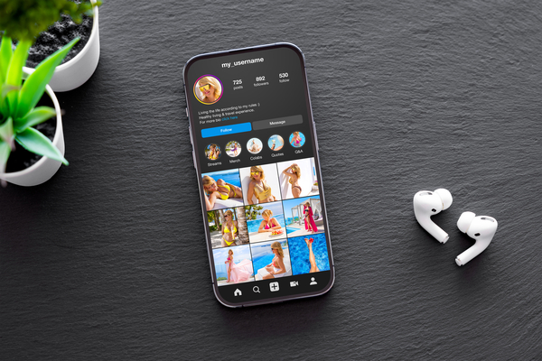 A smartphone and earbuds on a gray table.