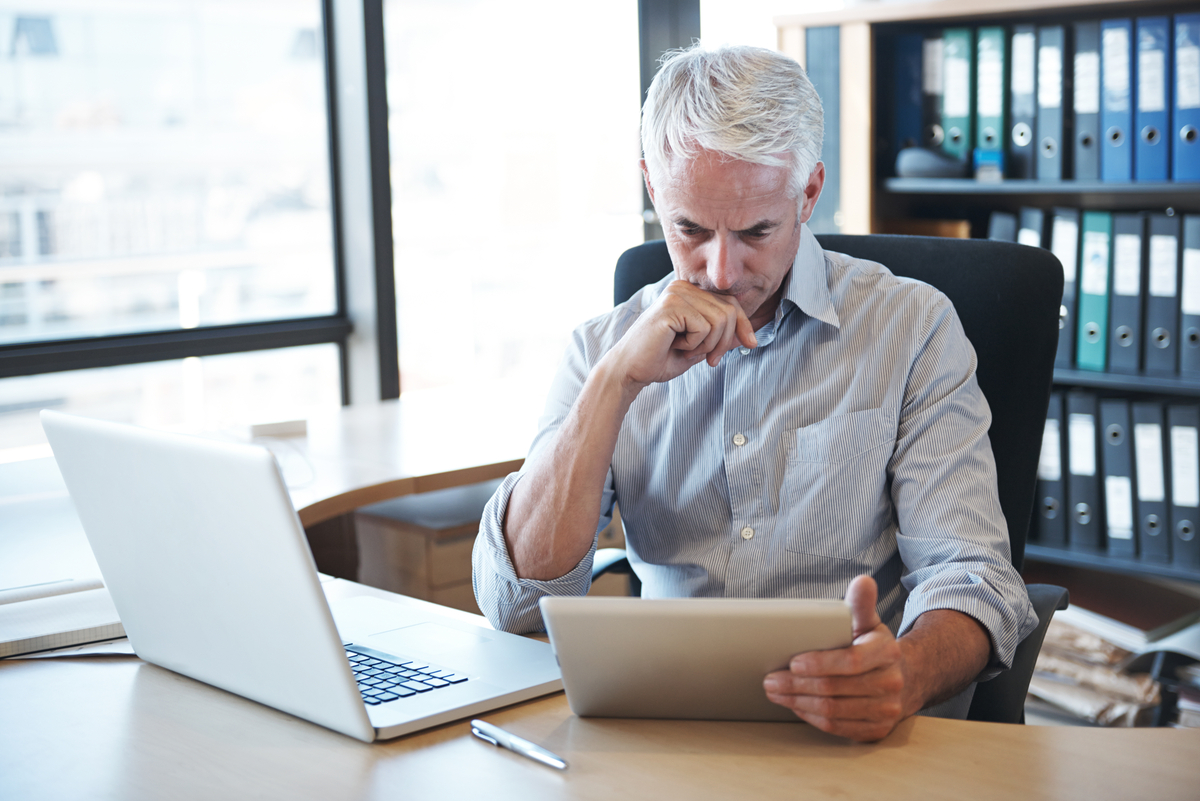 Person sitting at a desk and reading a tablet.